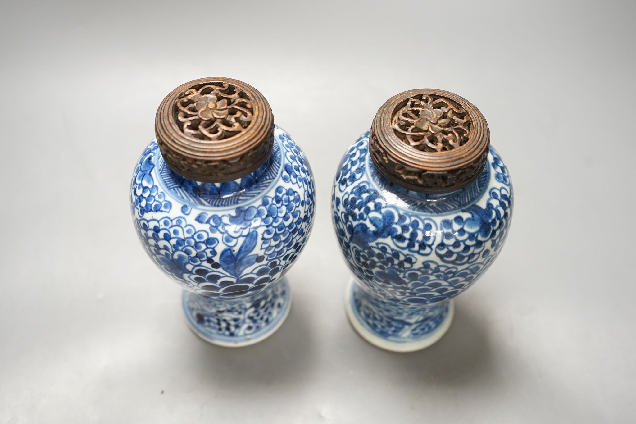 A pair of Chinese blue and white 'phoenix' vases, Kangxi, associated wood covers, 19cm including covers
